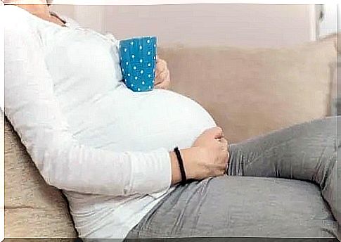 Pregnant woman with cup of tea on her belly